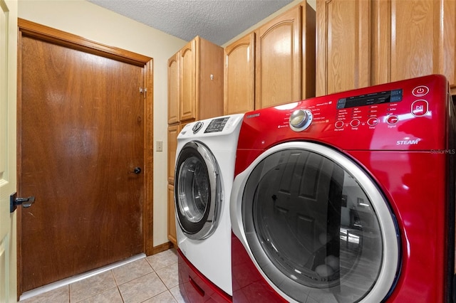 laundry room featuring cabinet space, washing machine and dryer, a textured ceiling, and light tile patterned flooring