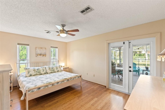 bedroom featuring a ceiling fan, access to outside, light wood-style floors, and visible vents