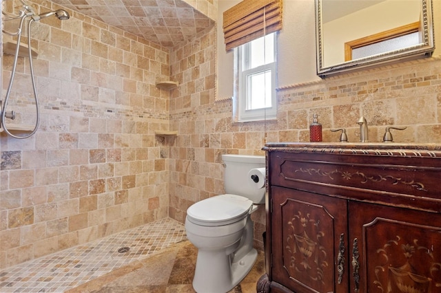 full bath featuring a tile shower, toilet, vanity, and tile walls