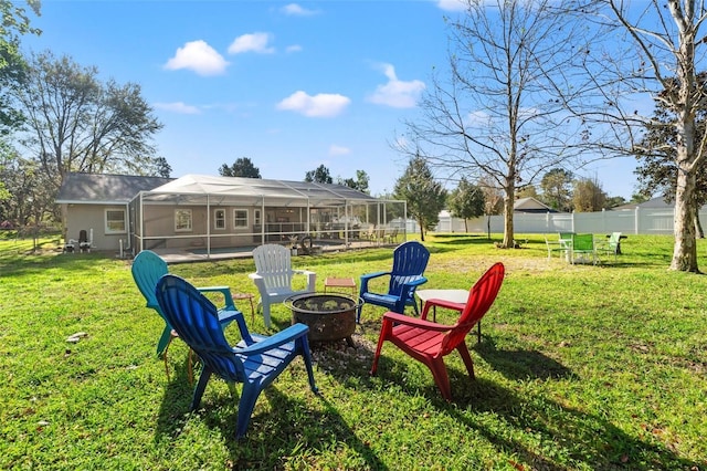 view of yard with a lanai, a fire pit, and fence