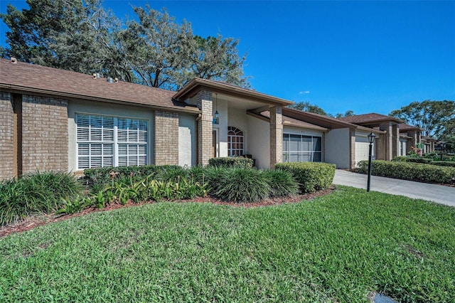 view of front of house featuring brick siding, a garage, driveway, and a front lawn