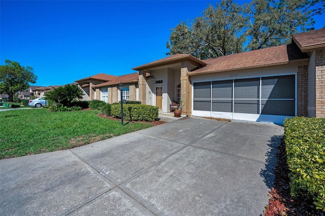 view of front facade with a front yard, an attached garage, brick siding, and driveway