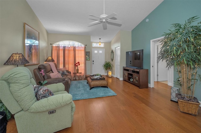 living room with baseboards, lofted ceiling, wood finished floors, and a ceiling fan