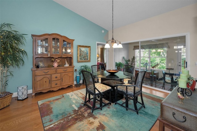 dining room with light wood-type flooring, baseboards, high vaulted ceiling, and a chandelier