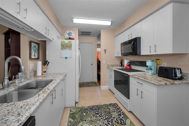 kitchen featuring visible vents, a textured ceiling, white appliances, white cabinetry, and a sink