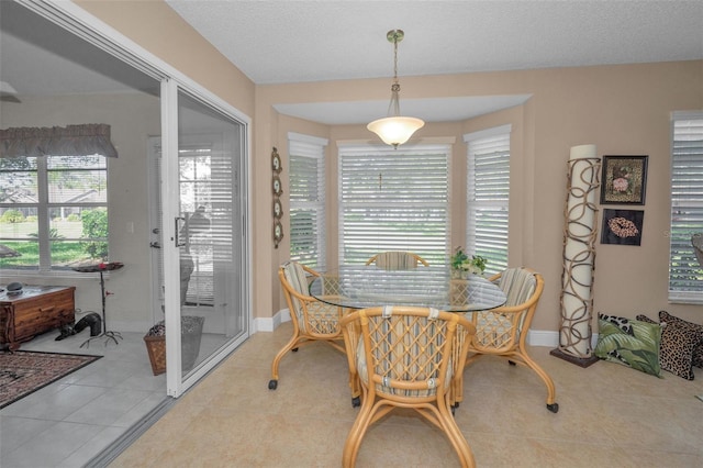 dining space with light tile patterned floors, a textured ceiling, and baseboards