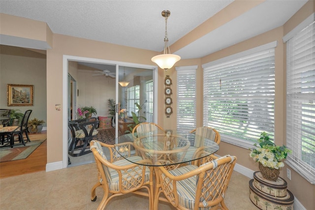 dining area featuring light tile patterned floors, baseboards, plenty of natural light, and a textured ceiling