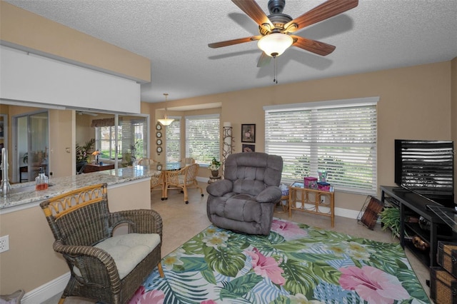 living area featuring a textured ceiling, a healthy amount of sunlight, and ceiling fan