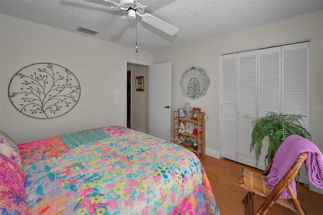 bedroom featuring a closet, visible vents, a textured ceiling, and wood finished floors