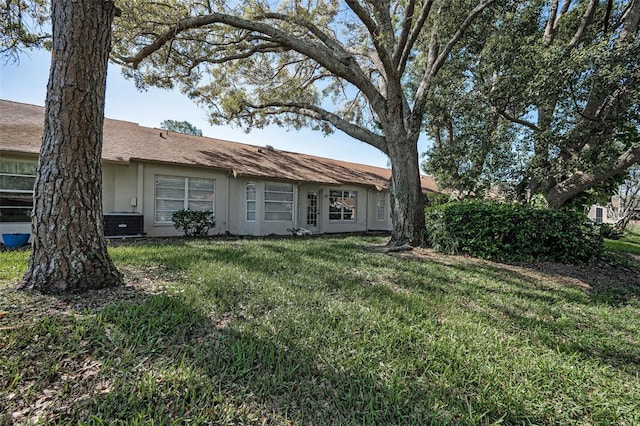 view of front of house featuring stucco siding, cooling unit, and a front yard