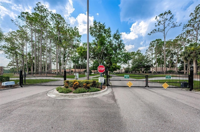 view of road featuring traffic signs, curbs, a gated entry, and a gate