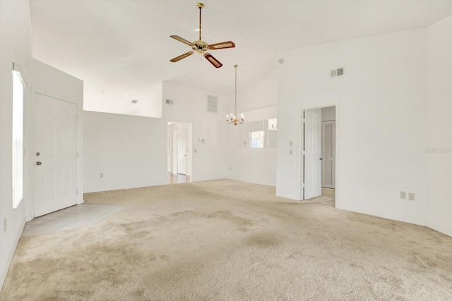 spare room with visible vents, light colored carpet, high vaulted ceiling, and ceiling fan with notable chandelier