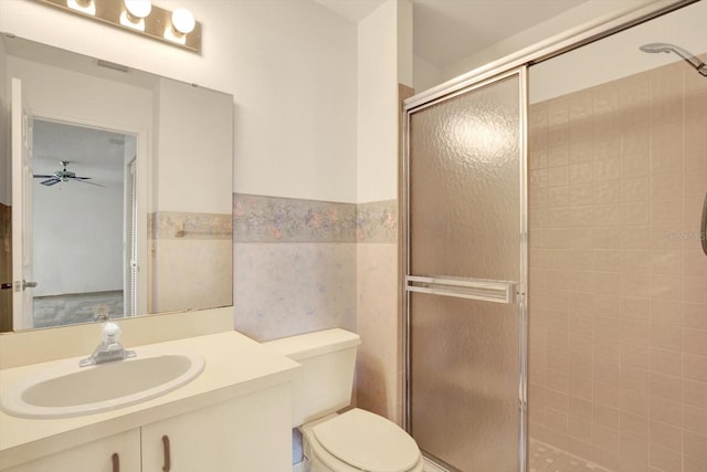 bathroom with vanity, a ceiling fan, a stall shower, tile walls, and toilet