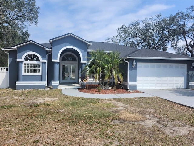 ranch-style house with a garage, driveway, french doors, roof with shingles, and stucco siding