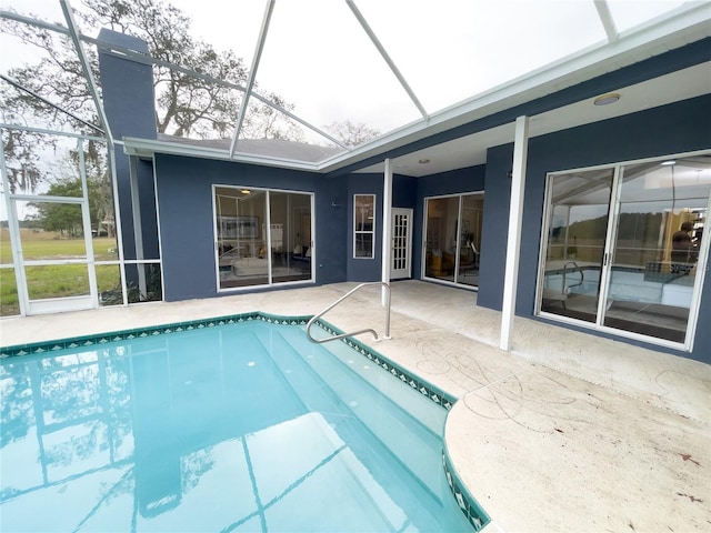 outdoor pool featuring glass enclosure and a patio