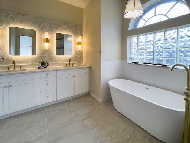 bathroom with a sink, a freestanding bath, and double vanity