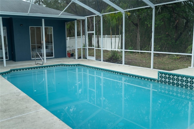 pool with glass enclosure, fence, and a patio