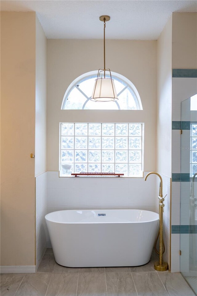 bathroom featuring a soaking tub, tile walls, and a shower stall