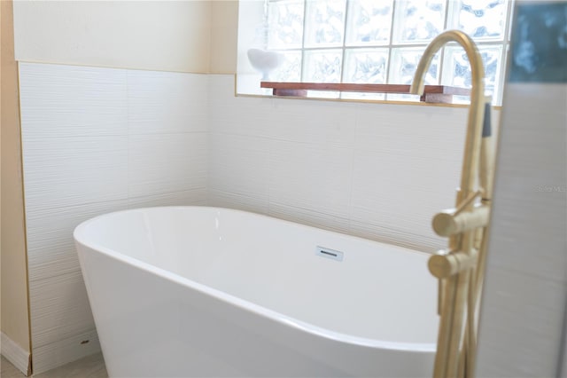 full bath with a soaking tub and tile walls