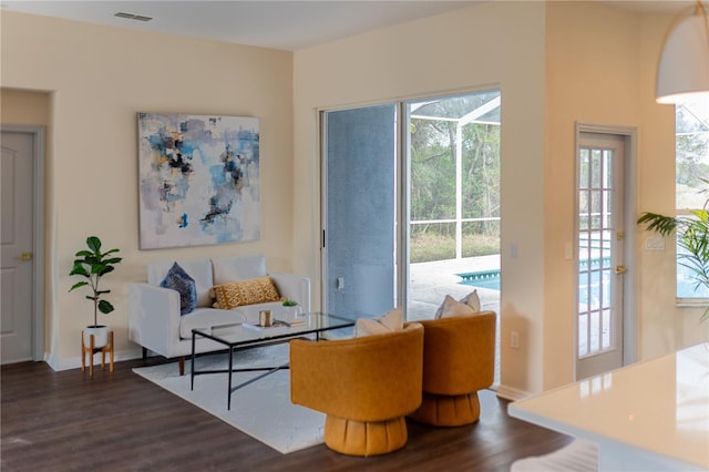 living area with dark wood finished floors, visible vents, and baseboards