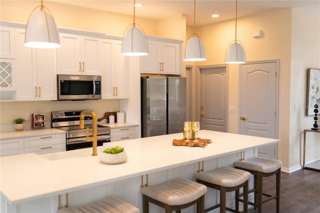 kitchen featuring a breakfast bar area, recessed lighting, appliances with stainless steel finishes, dark wood-type flooring, and white cabinets