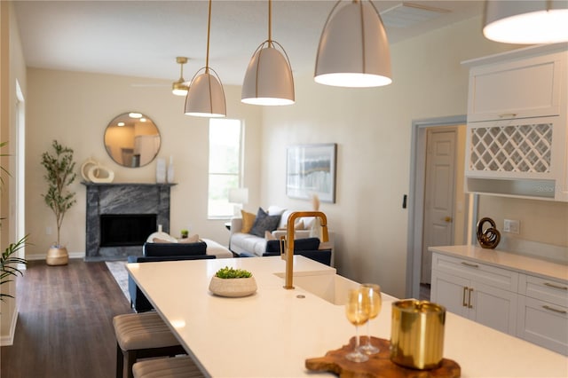 kitchen featuring dark wood finished floors, a premium fireplace, a breakfast bar area, light countertops, and white cabinetry