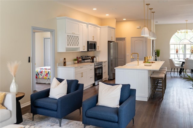 kitchen featuring stainless steel appliances, light countertops, open floor plan, white cabinetry, and an island with sink