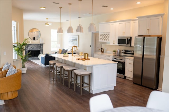 kitchen featuring stainless steel appliances, light countertops, open floor plan, white cabinetry, and a kitchen breakfast bar