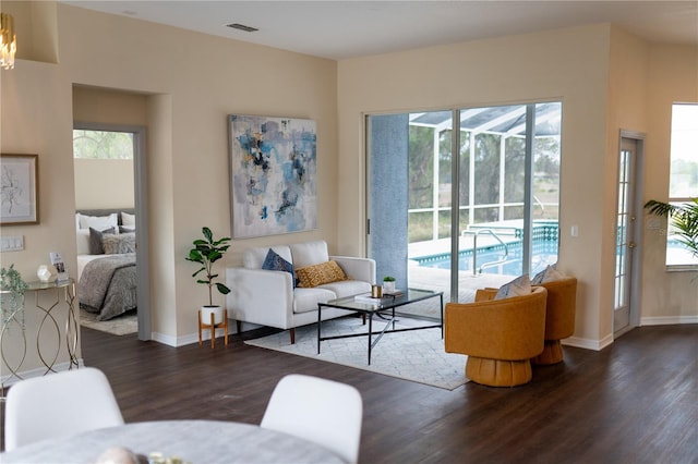 living area featuring baseboards, plenty of natural light, visible vents, and wood finished floors