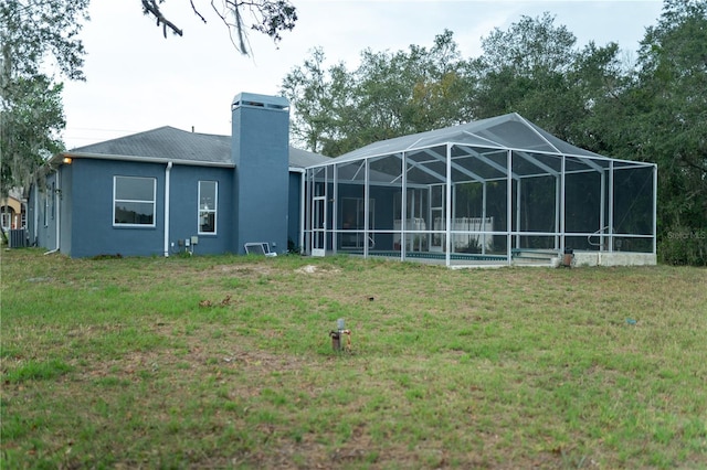 back of house with a yard, a chimney, stucco siding, glass enclosure, and an outdoor pool