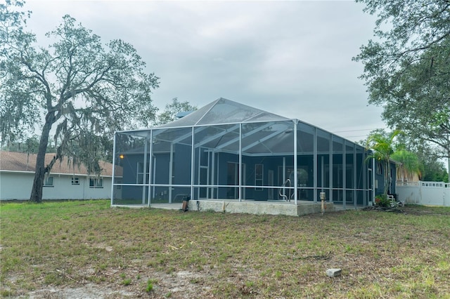 back of property with a yard, fence, and glass enclosure