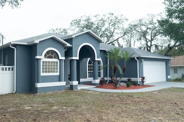 ranch-style home with driveway, an attached garage, a front yard, and stucco siding