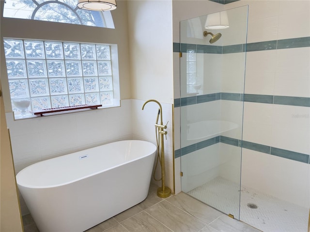 full bath featuring a freestanding tub, tile walls, and a walk in shower