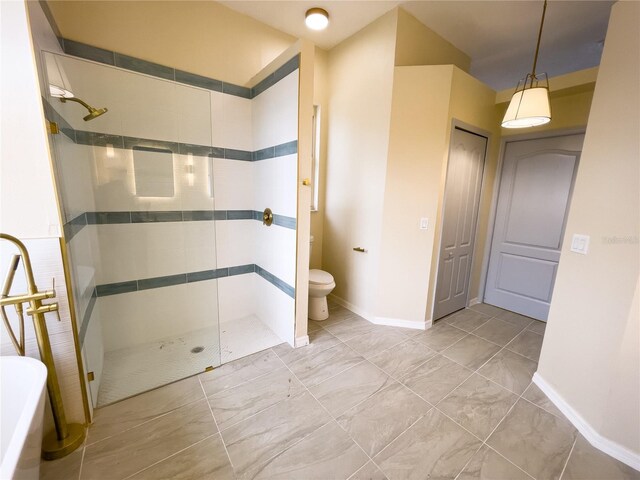 bathroom with toilet, baseboards, and a tile shower