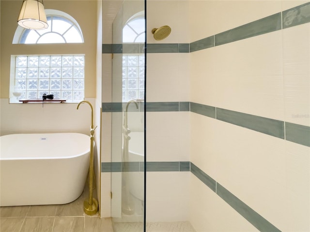 full bath featuring a soaking tub and a tile shower