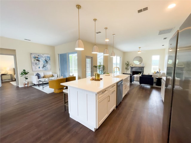 kitchen featuring dark wood finished floors, stainless steel appliances, visible vents, open floor plan, and white cabinetry