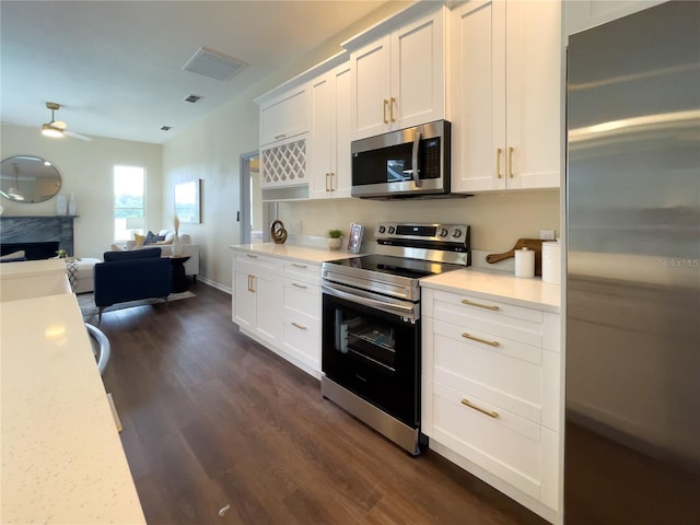 kitchen with visible vents, a high end fireplace, open floor plan, appliances with stainless steel finishes, and dark wood finished floors