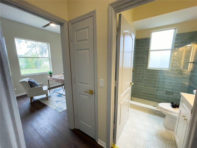 bathroom with toilet, a stall shower, baseboards, and wood finished floors