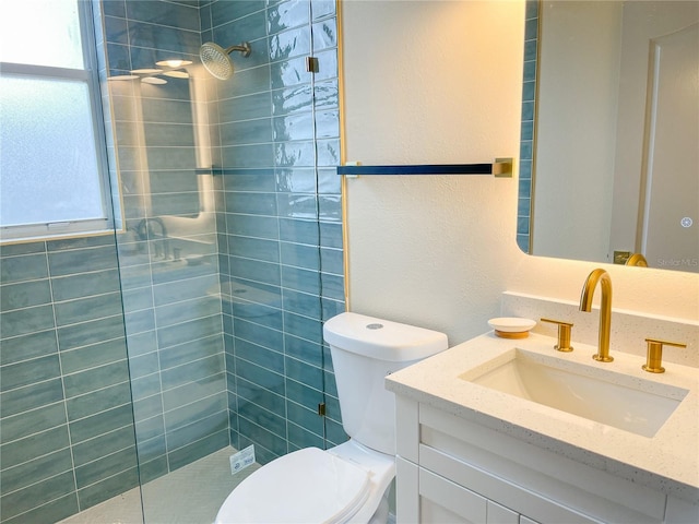 full bath with a textured wall, vanity, a tile shower, and toilet