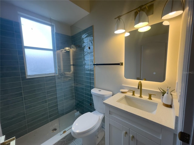 full bathroom with a tile shower, vanity, and toilet