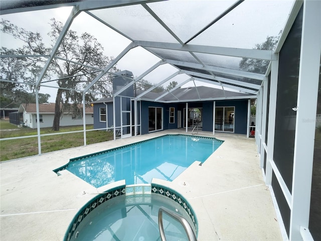 view of swimming pool with glass enclosure, a pool with connected hot tub, a lawn, and a patio