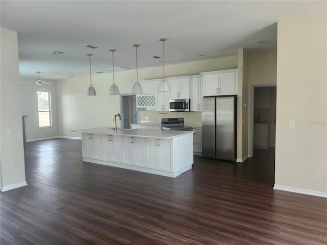 kitchen featuring dark wood finished floors, light countertops, appliances with stainless steel finishes, a kitchen island with sink, and white cabinetry