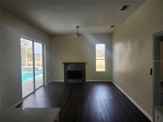 unfurnished living room featuring plenty of natural light, dark wood-style flooring, visible vents, and a fireplace