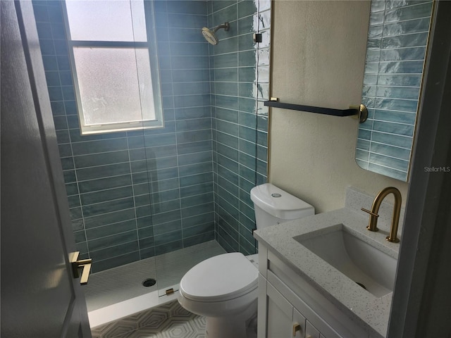 full bath with toilet, a textured wall, a shower stall, and vanity