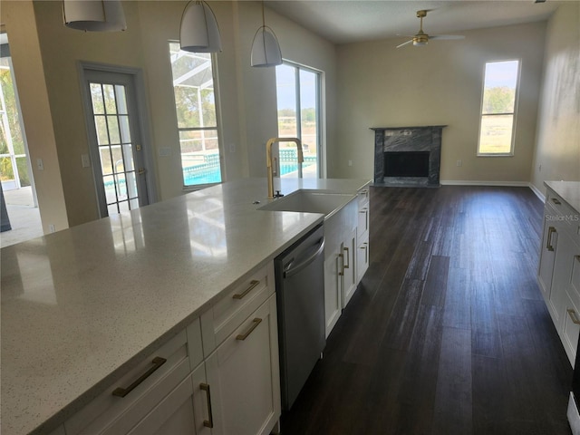 kitchen featuring dark wood finished floors, dishwasher, a premium fireplace, white cabinetry, and a sink