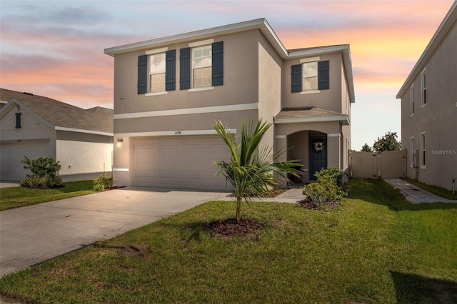 traditional home featuring stucco siding, a lawn, a gate, concrete driveway, and a garage