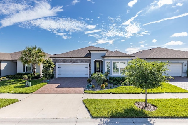 view of front of house with an attached garage, a front yard, decorative driveway, and stucco siding