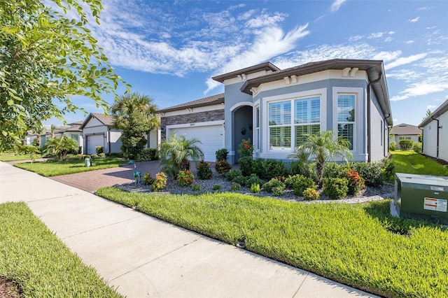 view of front of property featuring a garage, a front lawn, decorative driveway, and stucco siding