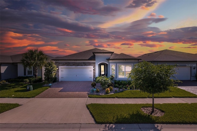 view of front facade with an attached garage, a yard, decorative driveway, and stucco siding