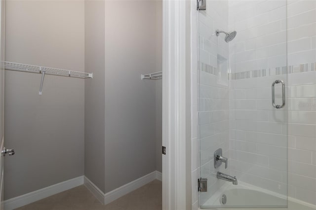 bathroom featuring shower / bath combination with glass door, tile patterned floors, and baseboards